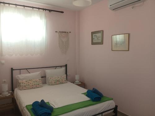 ein Schlafzimmer mit einem Bett mit blauen Kissen und einem Fenster in der Unterkunft Trizinia View in Galatás