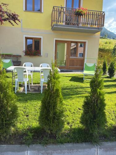 a house with a table and chairs in the yard at Appartamenti Mosconi Mistica in Vermiglio