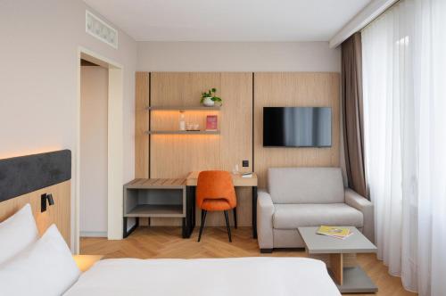a hotel room with a desk and a chair at Tailormade Hotel METROPOL St Gallen in St. Gallen