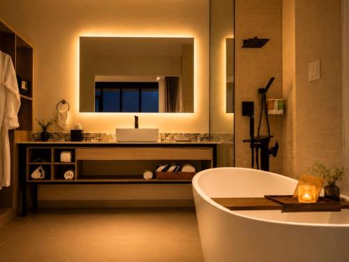 a bathroom with a tub and a sink and a mirror at Grand Resort & Residences in Belize City