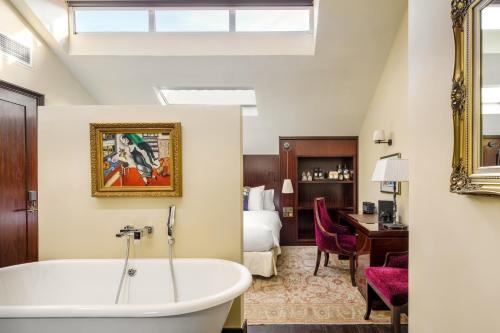 a hotel room with a tub and a bedroom at The Vagabond Club, a Tribute Portfolio Hotel Singapore in Singapore