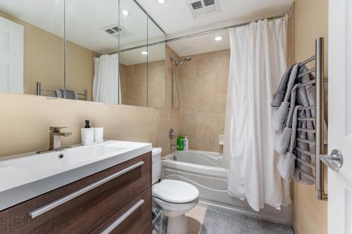 a bathroom with a sink and a toilet and a tub at Designer Apartment in Prime Location in Mississauga