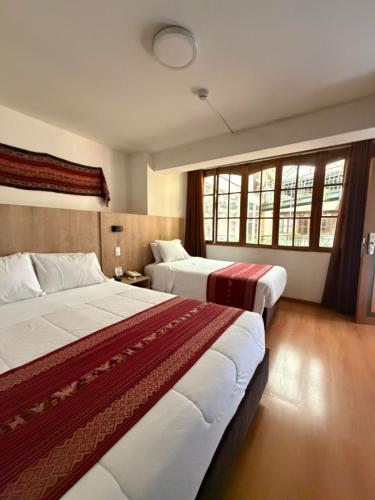 a hotel room with two beds and windows at Hotel Prisma Cusco in Cusco