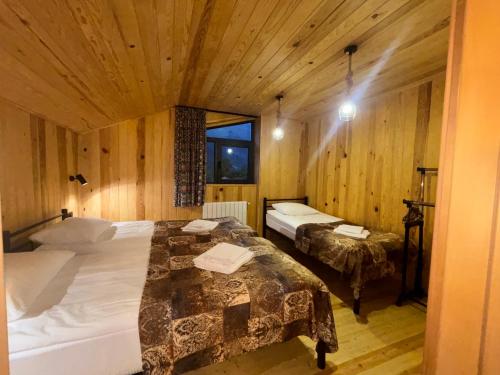 a bedroom with two beds in a room with wooden walls at Guesthouse Laurbili in Mestia