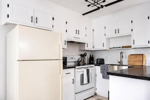 a white kitchen with white cabinets and a refrigerator at The PanAm fire pit bbq kid & dog friendly in Pensacola