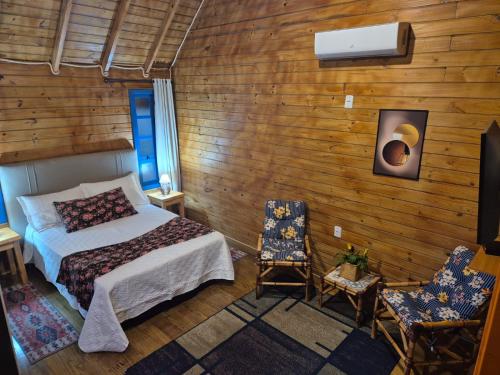 a bedroom with a bed and two chairs at Cabanas Laura in São Francisco de Paula