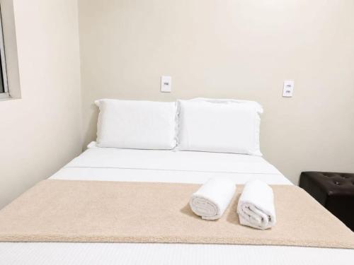 a bed with white pillows and towels on it at Pousada Aurora Nascer do sol 1 in Manhã