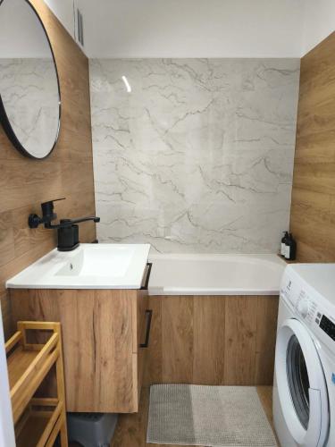 a bathroom with a sink and a washing machine at Apartament Kaszmirowy in Gorlice