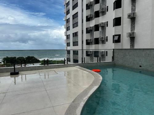 a large building with a swimming pool next to the ocean at Beach Class Executive - Flats no Pina por Yolo in Recife