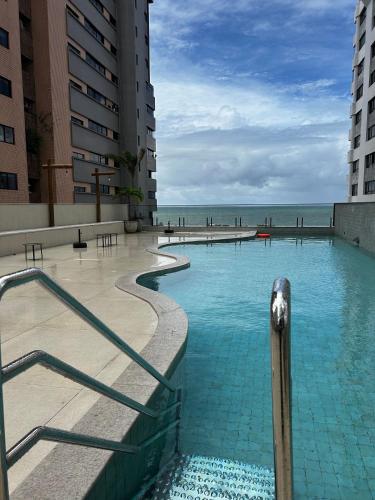 a swimming pool next to some buildings and the ocean at Beach Class Executive - Flats no Pina por Yolo in Recife