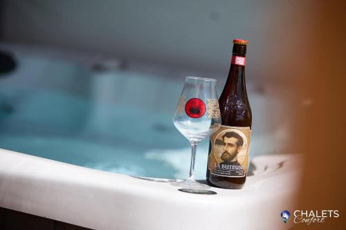 a bottle of beer next to a wine glass at Chalet L'Ascension in Saint-Philémon