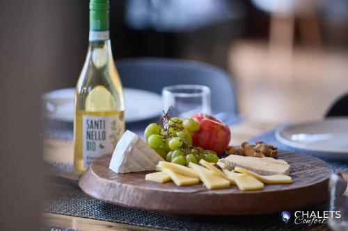 a plate of cheese and grapes and a bottle of wine at Chalet L'Ascension in Saint-Philémon