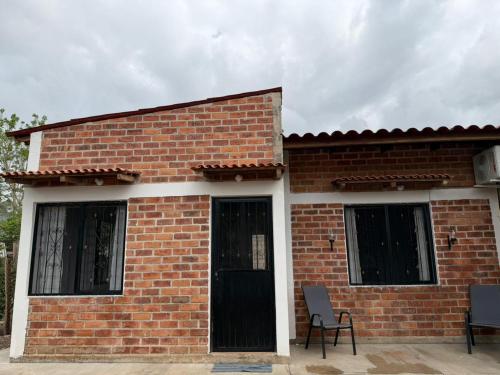 a brick house with two windows and two chairs at Casa ciruelo in Las Varas
