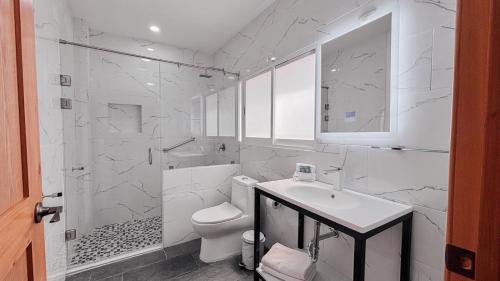 a white bathroom with a toilet and a sink at Hotel San Miguel, en el Centro - Desayuno Incluido in Tuxtla Gutiérrez
