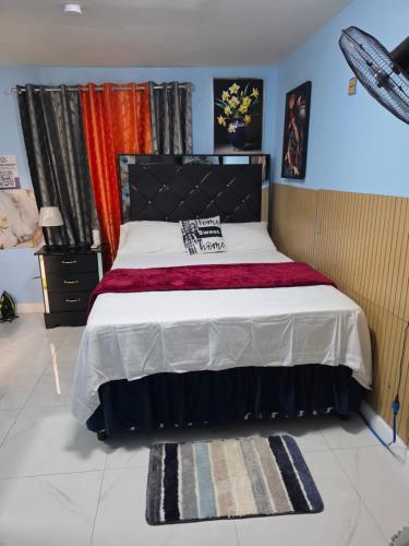 a bedroom with a large bed with a black headboard at BW Hideaway in Portmore