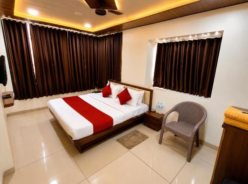a bedroom with a bed and a chair in it at Parth Paradise Hotel in Indore
