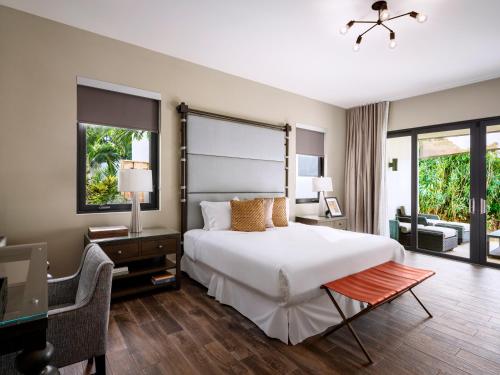 a bedroom with a large white bed and a desk and chair at The Loren at Pink Beach in Tuckerʼs Town