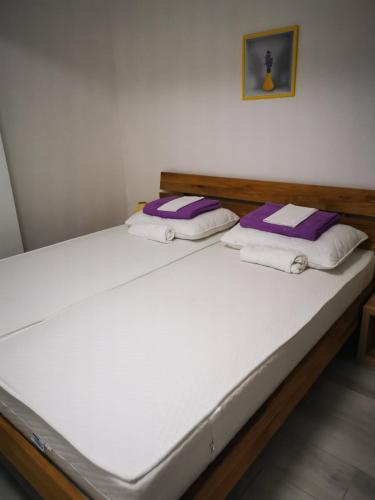 a bed with purple and white pillows on it at Apartments Škrobot in Senj