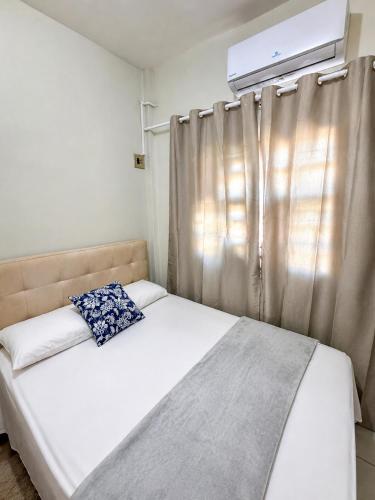 a bedroom with a bed and a window with avertisementatronatron at Apartamento no Centro da Cidade Nova in Marabá