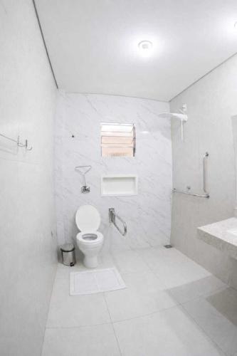 a white bathroom with a toilet and a sink at Hotel Refugio in Bonito