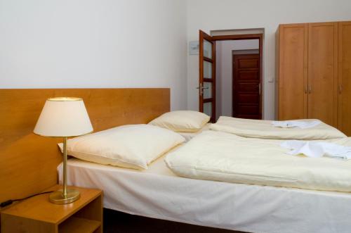 two beds in a room with a lamp on a table at Městský Hotel Dorinka in Hostinné