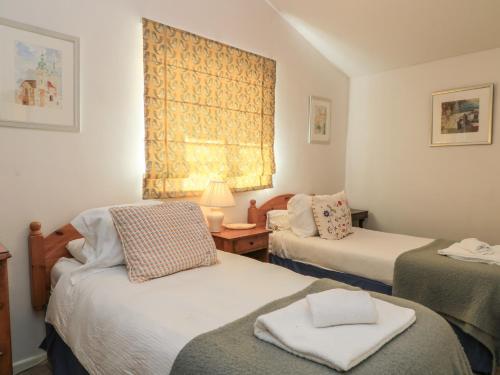 a small room with two beds and a window at Meadow Lodge in Cirencester