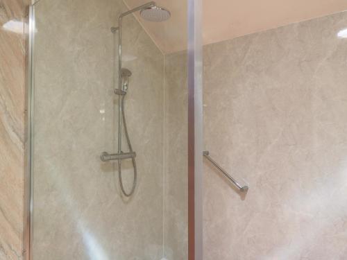 a shower with a glass door in a bathroom at Meadow Lodge in Cirencester