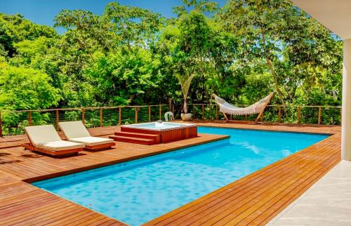a pool with chairs and a hammock on a deck at Green House Praia do Forte- 4 Suítes Premium in Mata de Sao Joao