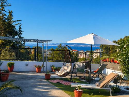 a patio with a swing and an umbrella at Little Villa - walk to the beach in Thessaloniki