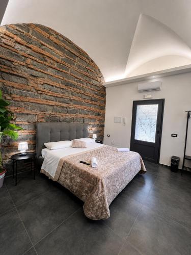 a bedroom with a large bed and a brick wall at Il Casale del 900 in Catania