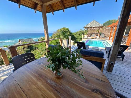 a wooden table with a plant on a deck with the ocean at Makana 3A in Ponta Mamoli