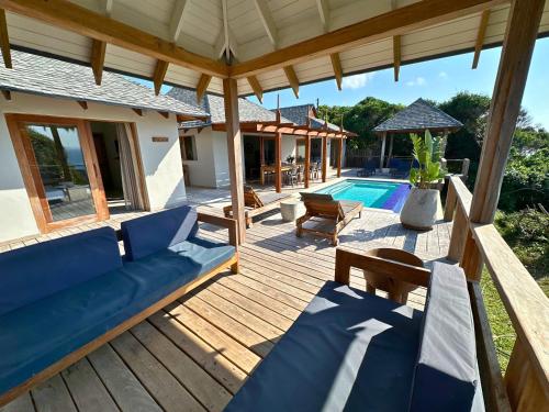 a wooden deck with chairs and a swimming pool at Makana 3A in Ponta Mamoli