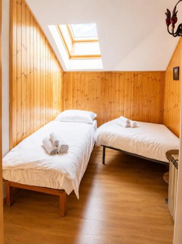 two beds in a room with a skylight at Appartamento Lisander in Ponte di Legno