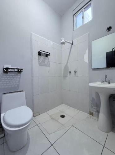 a white bathroom with a toilet and a sink at Feng tower in Culiacán