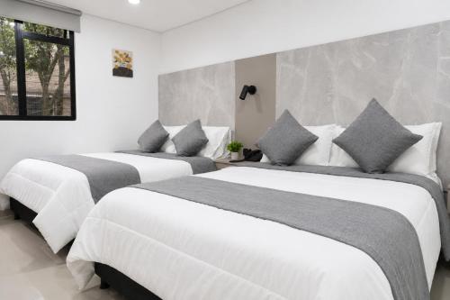 two beds in a room with white and gray at NOVA Apartahotel in Medellín