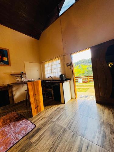 a room with a kitchen with a counter and a table at Chalé Recanto Figueira in Camanducaia