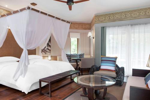 a bedroom with a bed and a table and chairs at Le Domaine Deva, Series by Marriott in Bourail
