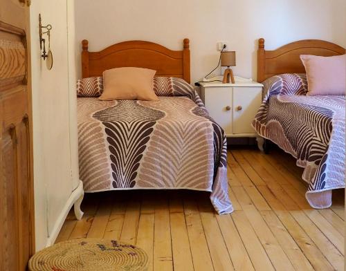 a bedroom with two beds and a wooden floor at Casa Rural Lutia in Andaluz