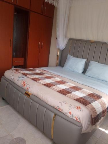 a bed with a plaid blanket on top of it at Spea Residency Apartment in Mbarara