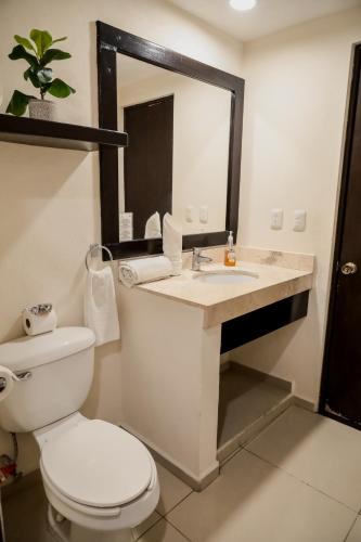a bathroom with a toilet and a sink with a mirror at Hotel Bogavante in Barra de Navidad