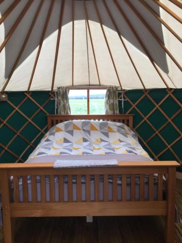 a bed in a yurt with a window at Yurt Ash tree in Saint Briavels
