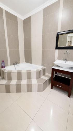 a bathroom with a bath tub and a sink at TLMZ Guesthouse in Newcastle