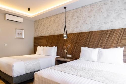 two beds in a hotel room with white sheets at Hotel Alma Boutique in Jiutepec