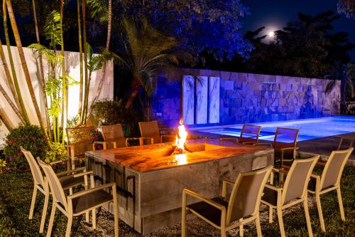 a table with chairs and a fire burns on it next to a pool at Hotel Alma Boutique in Jiutepec