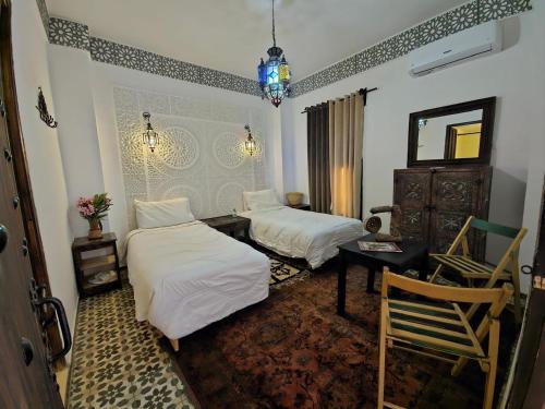 a bedroom with two beds and a table and a mirror at Hotel Atlas Gorge Dades in Boumalne Dades