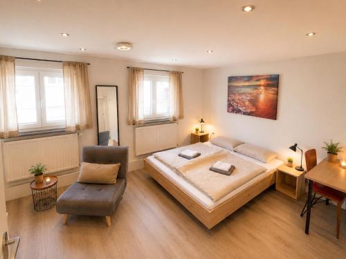 a large bedroom with a large bed and a chair at City Apart 3 nahe Badewelt, Museum & Bahnhof mit NETFLIX in Sinsheim