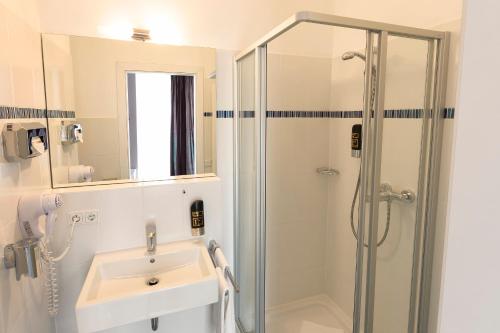 uma casa de banho com um lavatório e um chuveiro em Empress Boutique Hotel em Munique