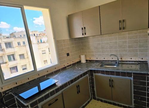 a kitchen with a sink and a large window at Morjan apart in Tangier