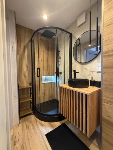 a bathroom with a shower with a sink and a mirror at MAX Apartaments in Częstochowa