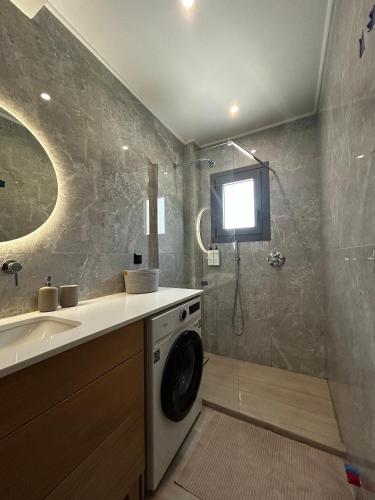 a bathroom with a washing machine and a tv on the wall at Tsonas Maisonette in Lygia